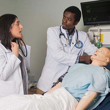 Two U N E Osteopathic Medicine students practicing on a dummy